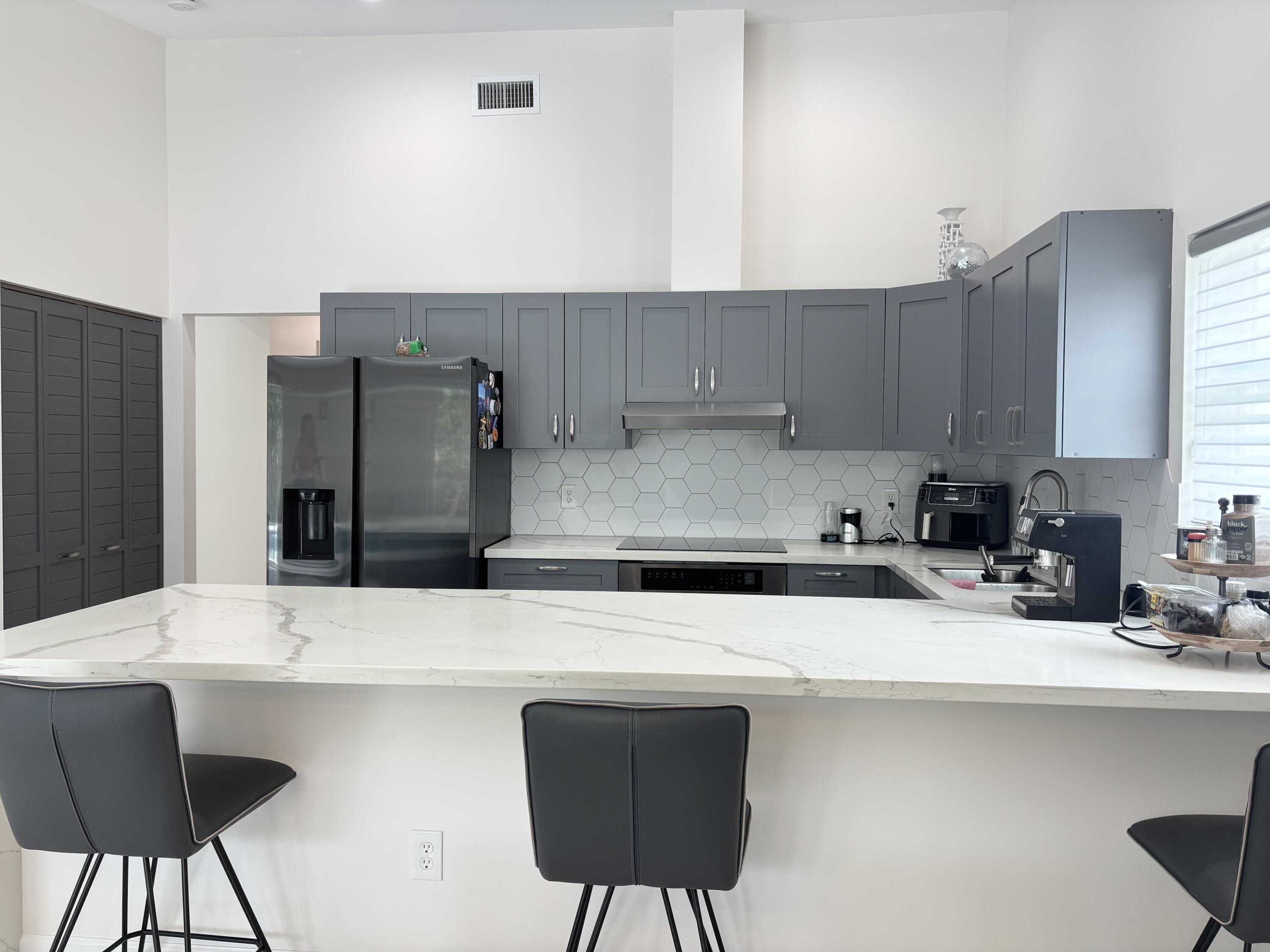330 Sandalwood Lane Boca Raton, FL 33487 - Photo 3 of 23 a kitchen with stainless steel appliances kitchen island a table chairs in it and wooden floors