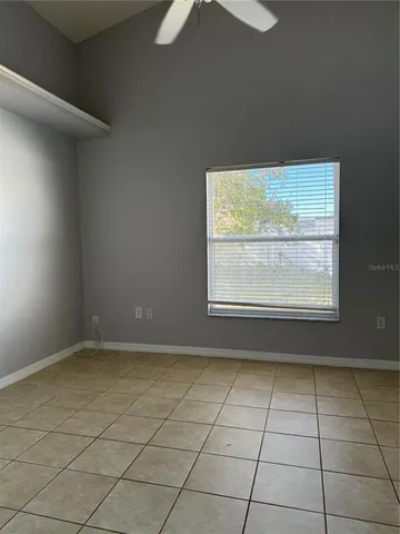 an empty room with windows and fan