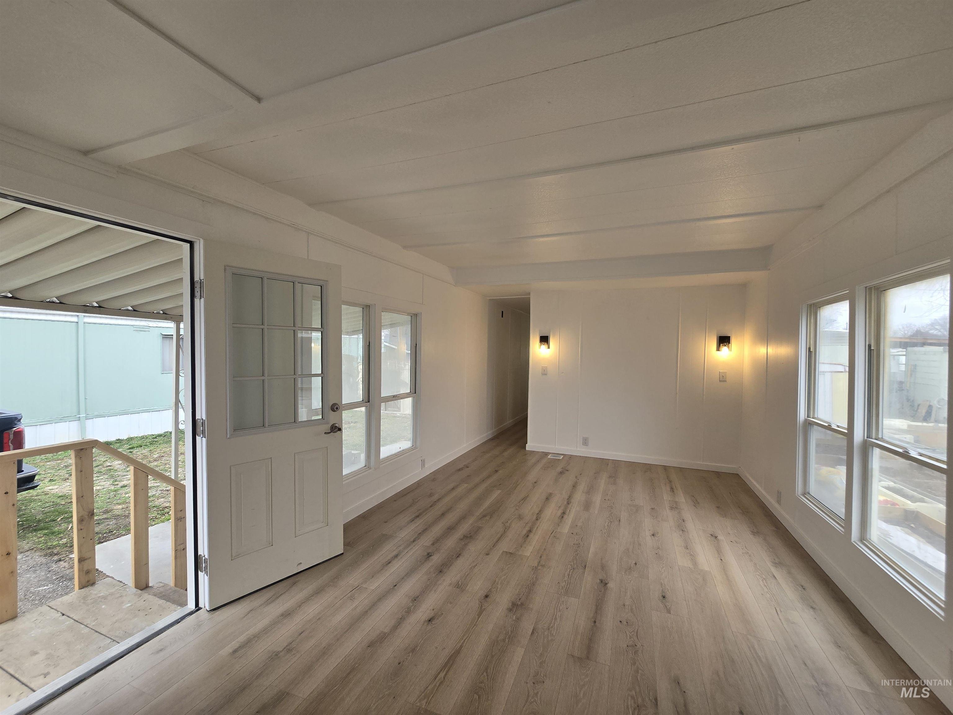 915 South Curtis Road, Unit 80 Boise, ID 83705 - Photo 3 of 12 Empty room featuring light wood finished floors and beamed ceiling