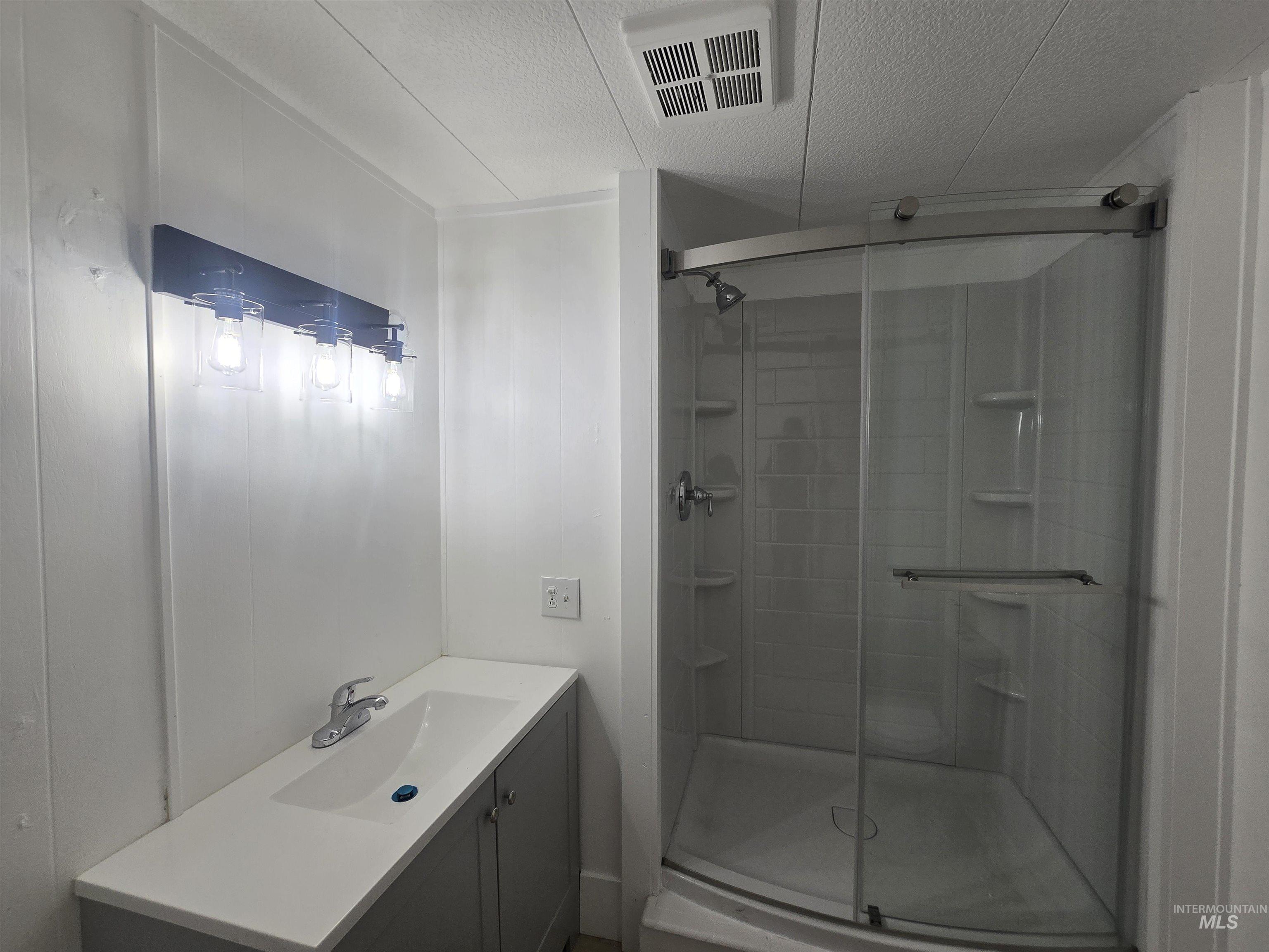 915 South Curtis Road, Unit 80 Boise, ID 83705 - Photo 6 of 12 Bathroom featuring vanity, a shower stall, and a textured ceiling