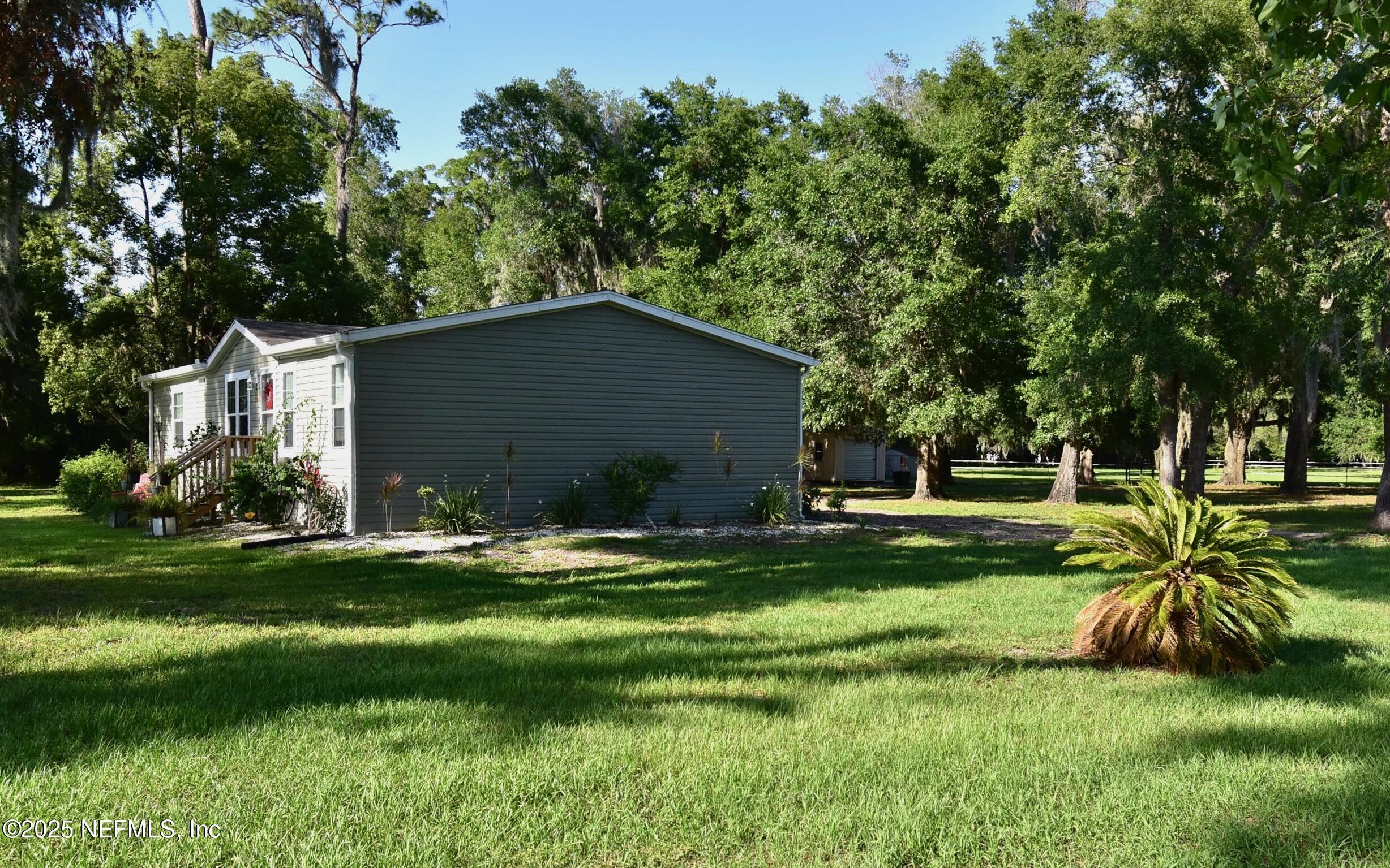 500 Georgetown Shortcut Road Georgetown, FL 32139 - Photo 2 of 59 a backyard of a house with table and chairs plants and large tree