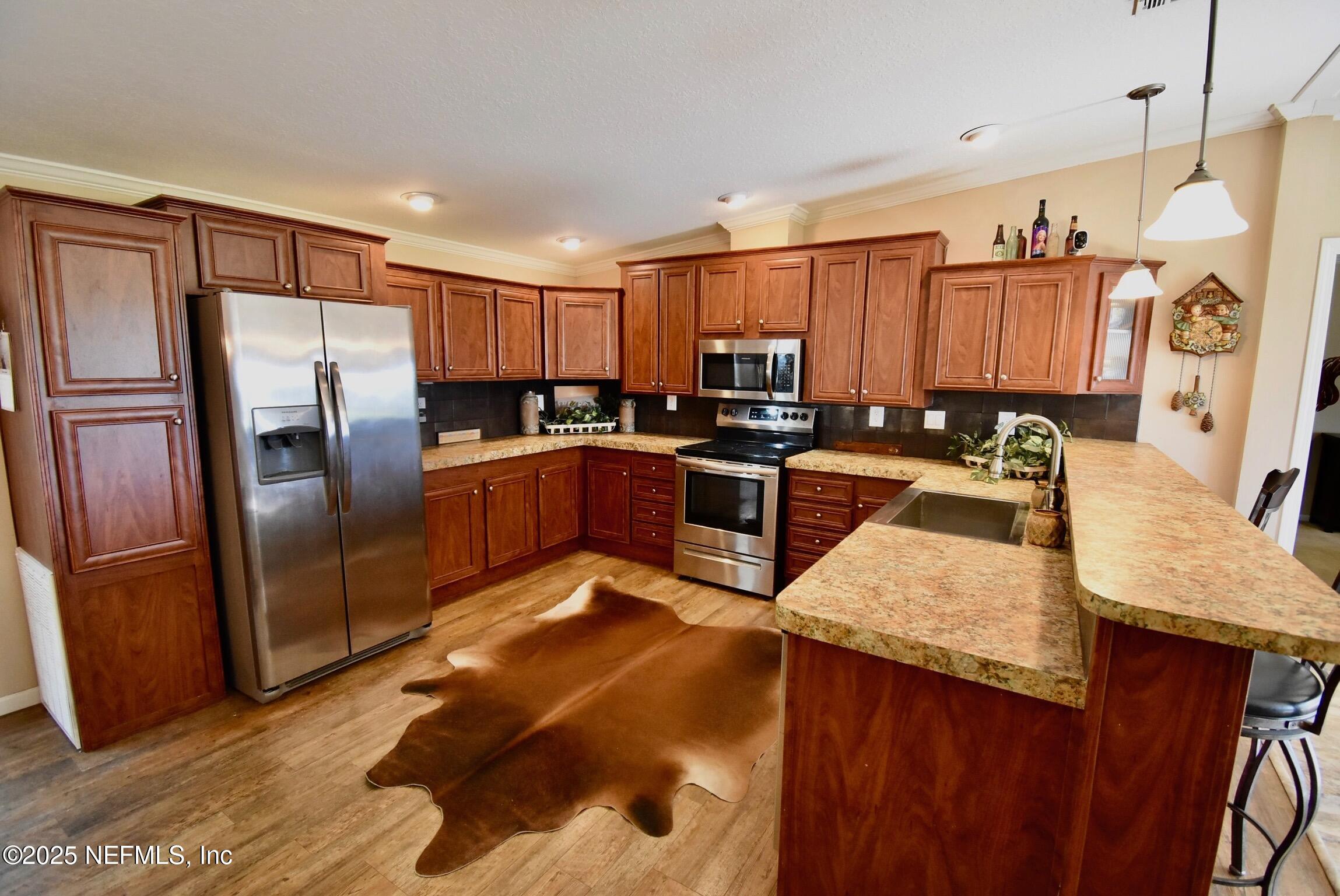 500 Georgetown Shortcut Road Georgetown, FL 32139 - Photo 29 of 59 a kitchen with stainless steel appliances granite countertop a refrigerator a stove and a sink with wooden cabinets