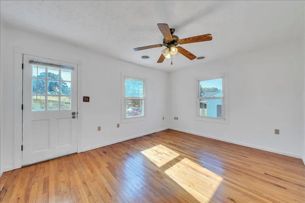 a view of empty room with wooden floor and fan