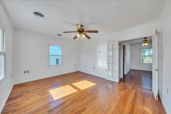 a view of empty room with wooden floor and fan