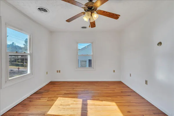 an empty room with wooden floor closet and windows