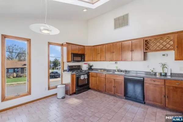a kitchen with stainless steel appliances granite countertop a stove top oven a sink dishwasher a dining table and chairs with wooden floor