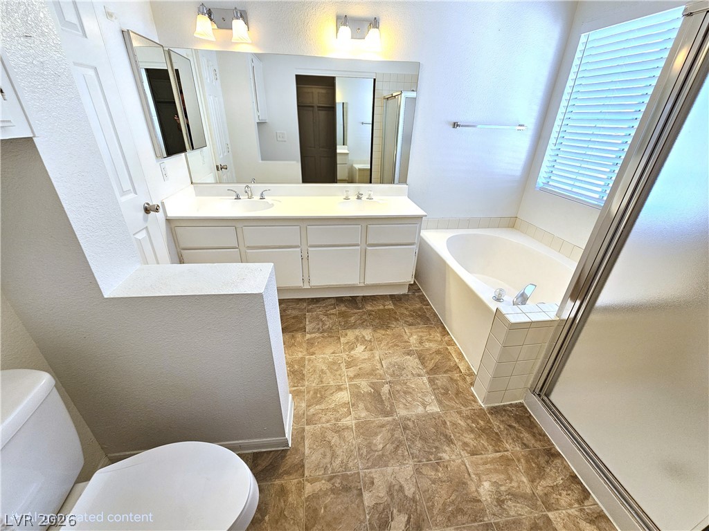 2817 Albemarle Way Henderson, NV 89014 - Photo 18 of 25 A functional primary bathroom offers a dual vanity, an inviting soaking tub, and a separate shower.