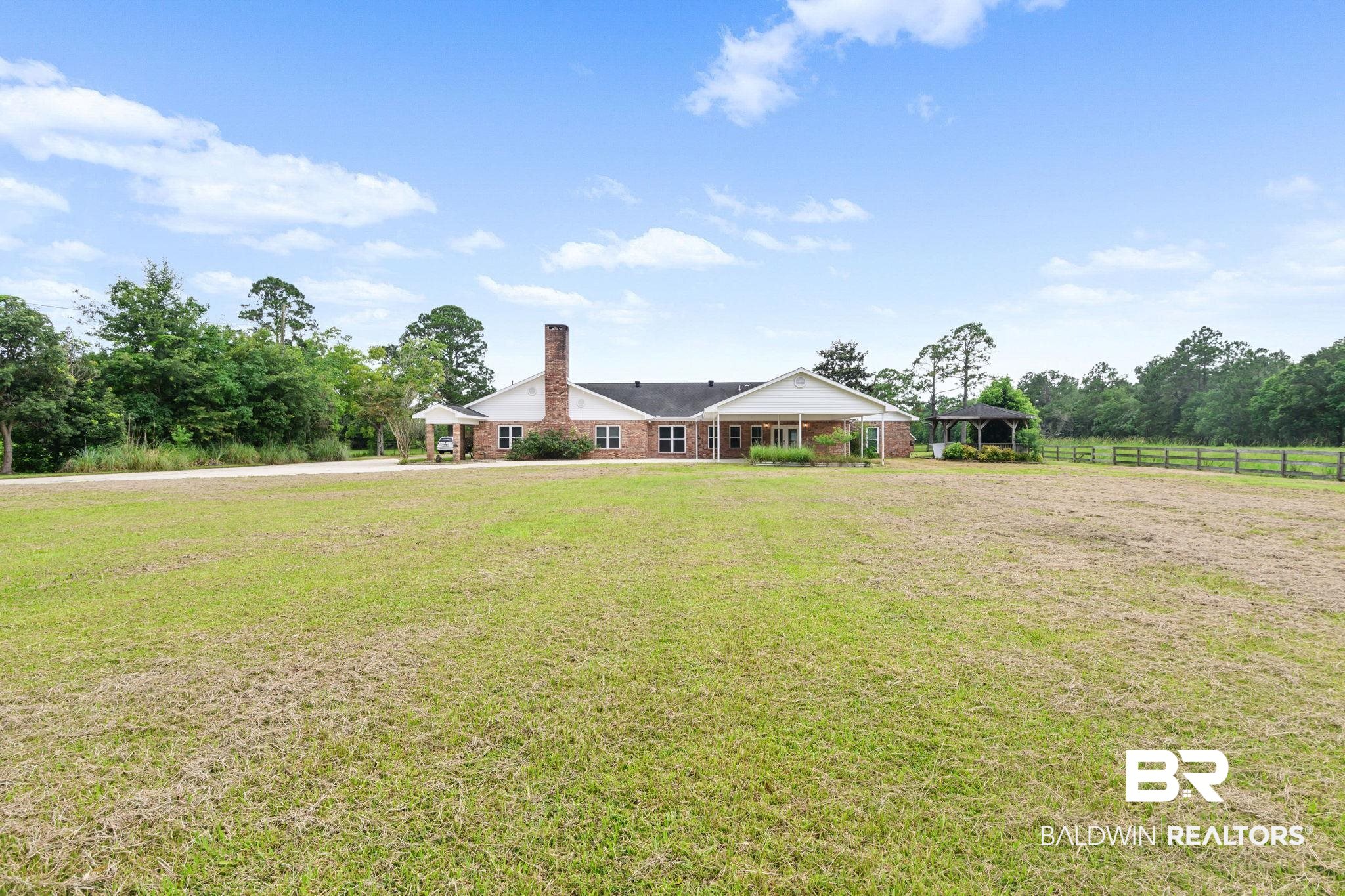 7540 2 Mile Road Irvington, AL 36544 - Photo 81 of 82 Sprawling brick exterior property featuring a large front lawn, a detached gazebo structure, a long driveway, and extensive perimeter fencing
