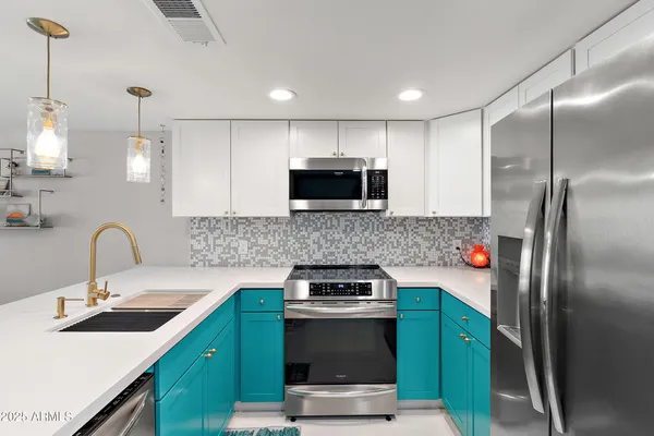 a kitchen with stainless steel appliances granite countertop a sink a stove a refrigerator and a microwave