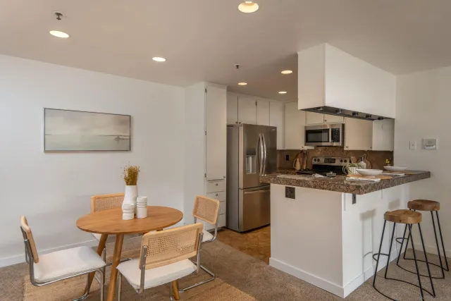 a kitchen with stainless steel appliances kitchen island granite countertop a dining table and chairs