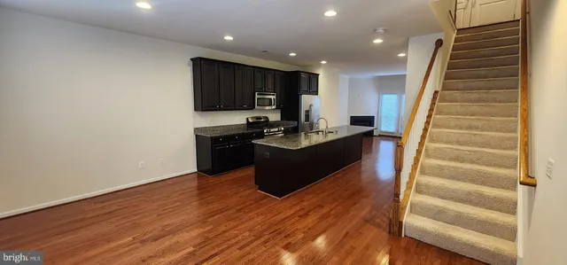 a living room with wooden floor furniture and a kitchen view