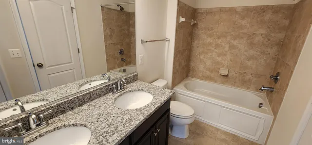 a bathroom with a granite countertop sink a toilet and bathtub