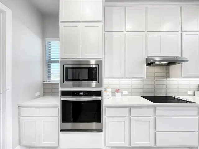 a kitchen with granite countertop white cabinets and white appliances