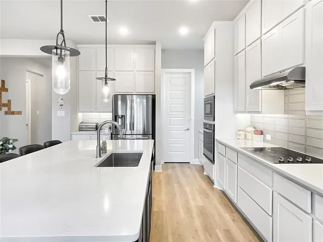 a kitchen with stainless steel appliances kitchen island granite countertop a sink stove and refrigerator