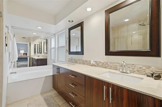 a bathroom with a sink double vanity granite tub shower and a mirror