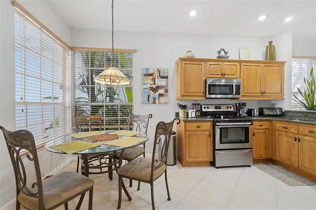 a kitchen with stainless steel appliances a stove a sink dishwasher a dining table and chair