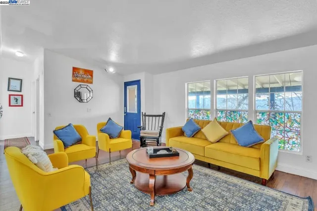 a living room with blue couches painting on wall and a large window
