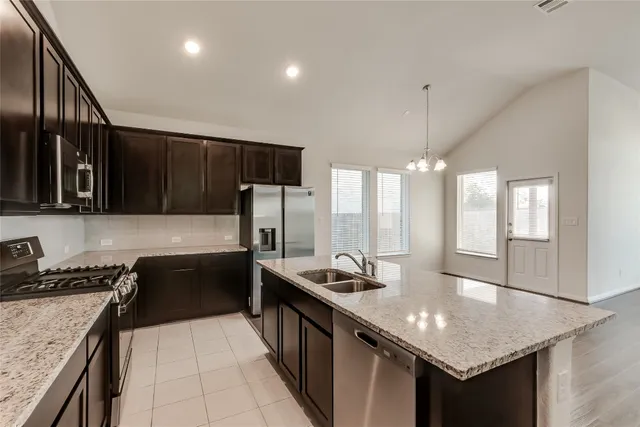 a kitchen with stainless steel appliances granite countertop a sink a stove and a refrigerator