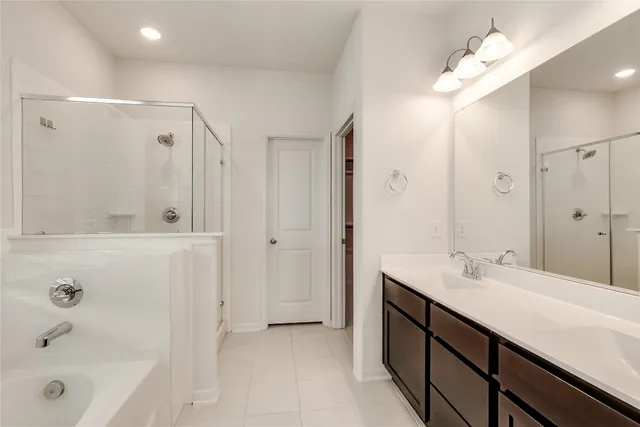 a bathroom with a tub sink double vanity and shower