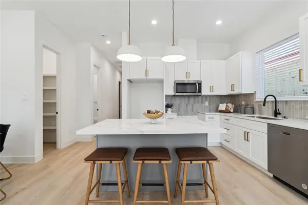 a kitchen with stainless steel appliances a table chairs stove and cabinets