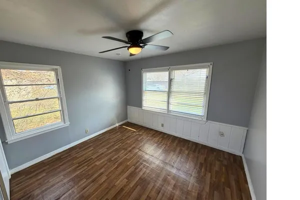a view of an empty room with window and wooden floor