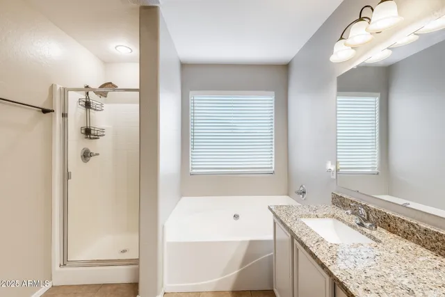a bathroom with a granite countertop bathtub a sink and a large mirror