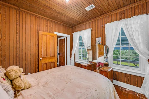 a bedroom with a bed and large windows