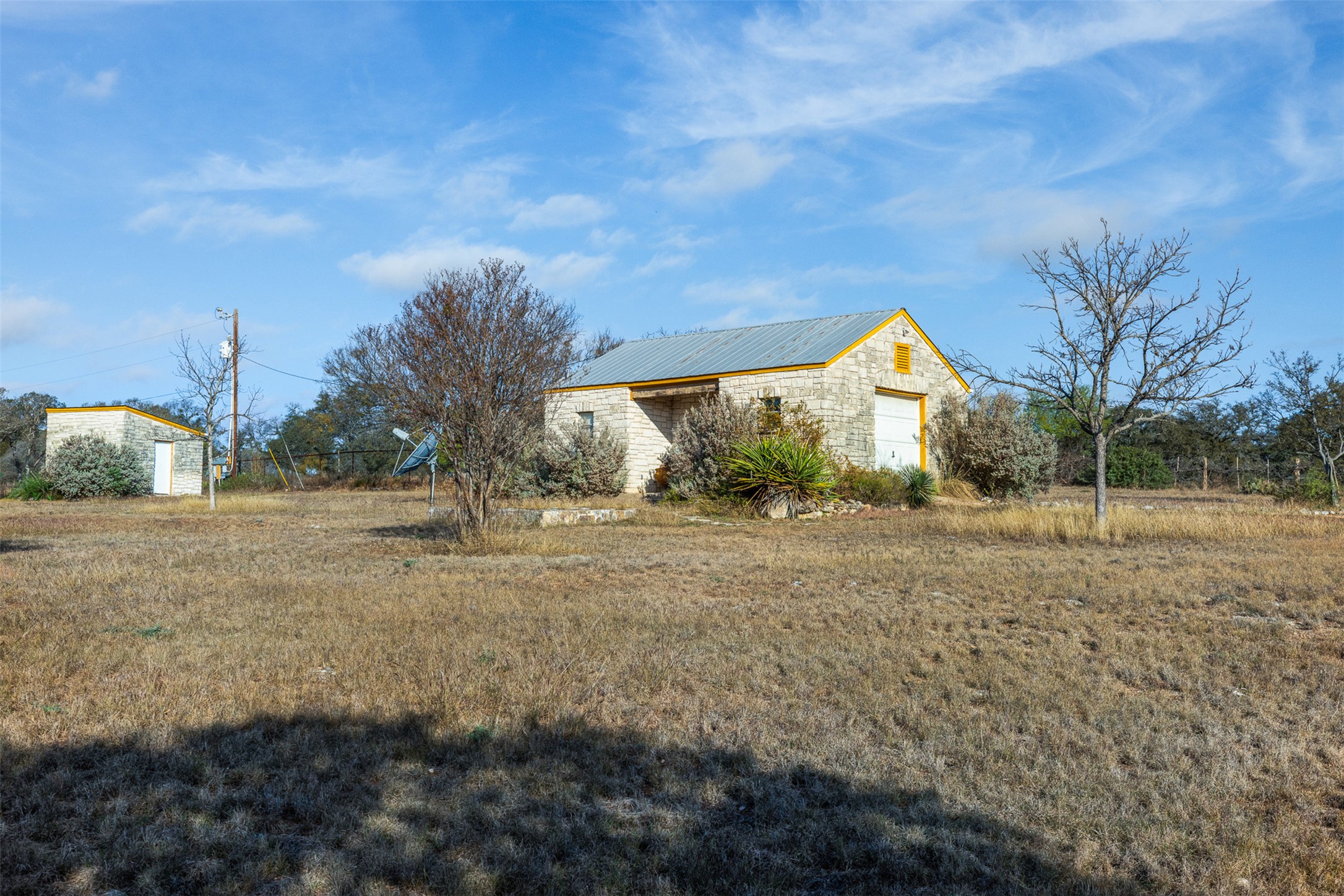 27701 Turner Ranch Road Marble Falls, TX 78654 - Photo 19 of 40 View of side of property featuring an outdoor structure, a metal roof, stone siding, and a garage
