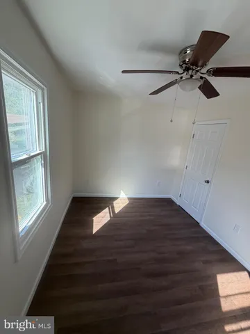 a living room with couches and kitchen view with wooden floor