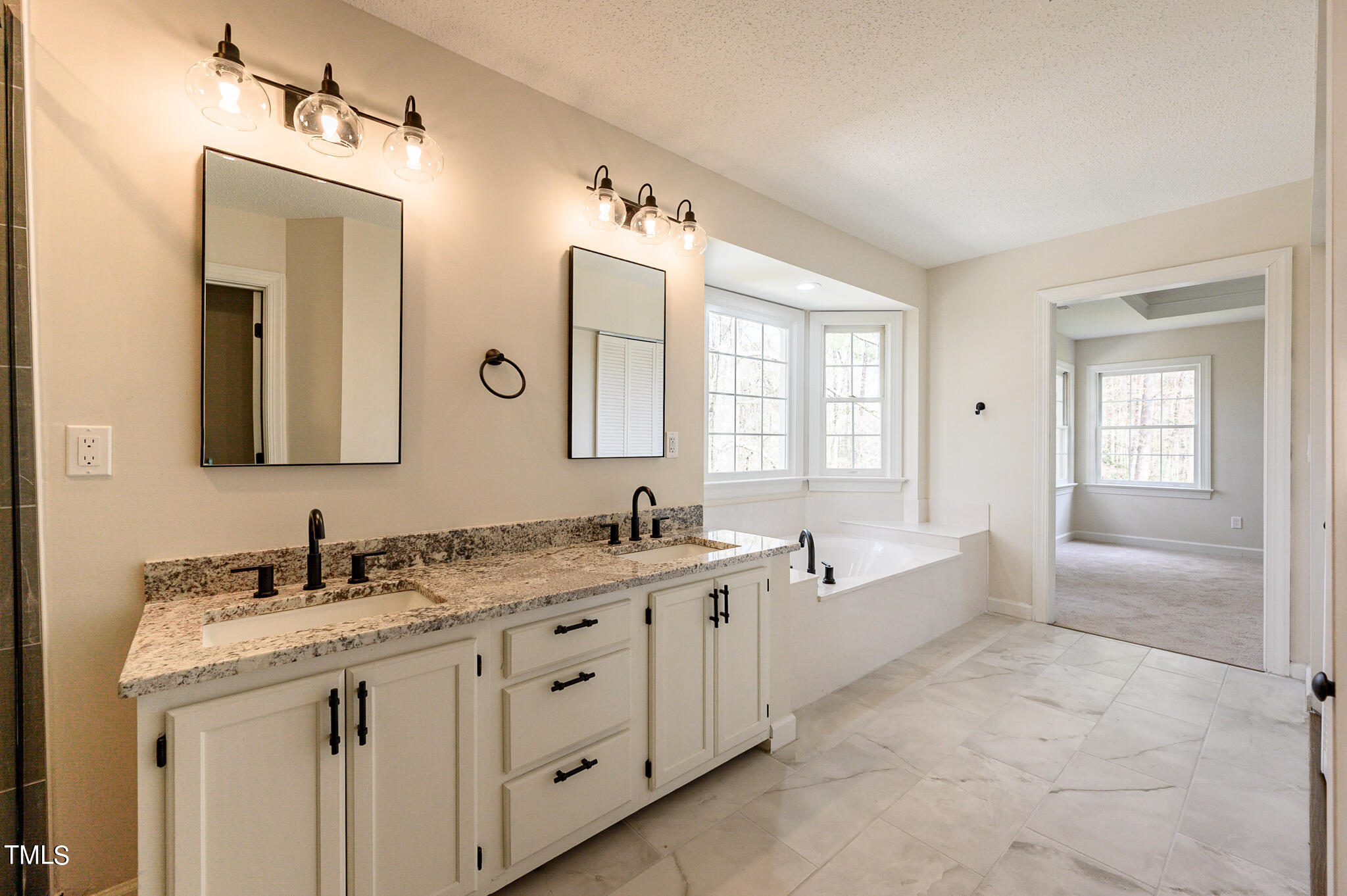 5620 Raddington Street Raleigh, NC 27613 - Photo 23 of 41 a spacious bathroom with a granite countertop double vanity sink a mirror and a bathtub