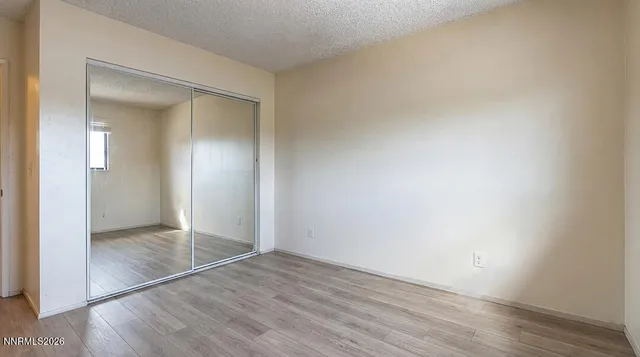 an empty room with wooden floor & closet area
