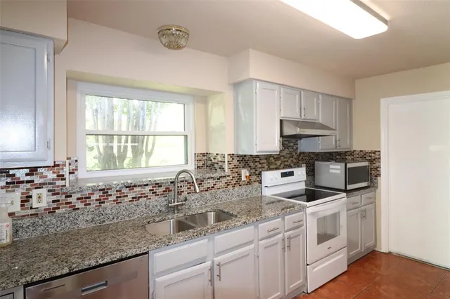a kitchen with stainless steel appliances granite countertop a sink a stove and cabinets