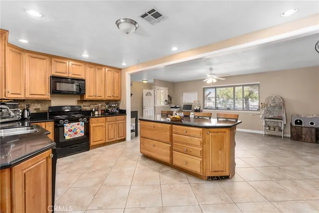 a large kitchen with kitchen island granite countertop a stove a sink a counter top space and cabinets