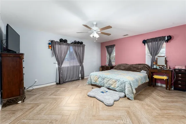 a spacious bedroom with a bed a dresser and a chandelier