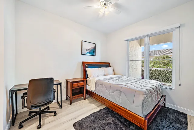 a bedroom with a bed a desk and chair with a bookshelf