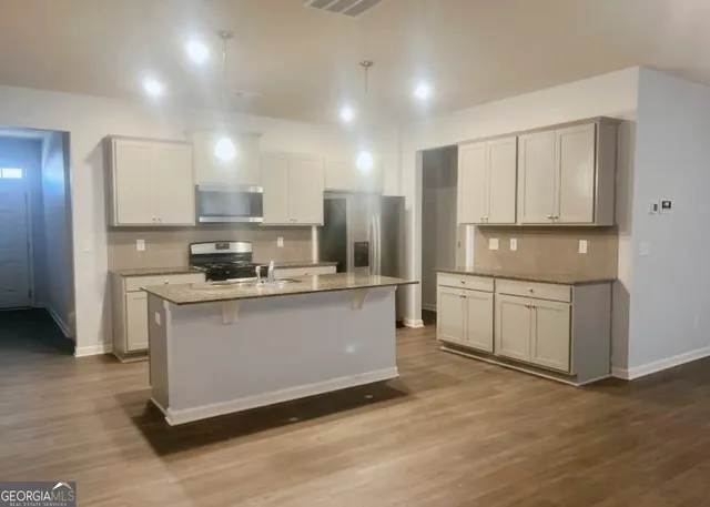 a kitchen with stainless steel appliances granite countertop a stove a sink and a refrigerator
