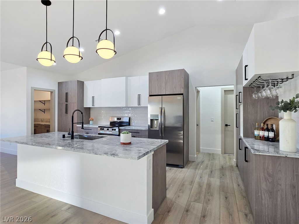 1120 West Gamebird Road Pahrump, NV 89048 - Photo 17 of 36 Kitchen with light stone countertops, stainless steel appliances, decorative light fixtures, white cabinetry, and decorative backsplash