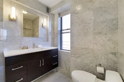 a bathroom with a toilet sink double vanity and mirror