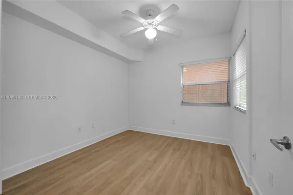 a view of a room with wooden floor and a ceiling fan