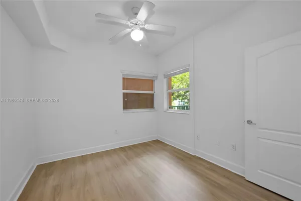 an empty room with a window and ceiling fan