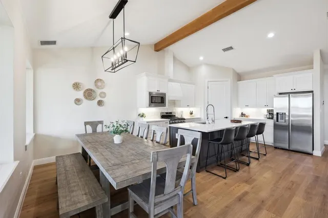 a dining room with stainless steel appliances kitchen island a table chairs and a refrigerator
