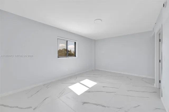 an empty room with a white cabinet and a window