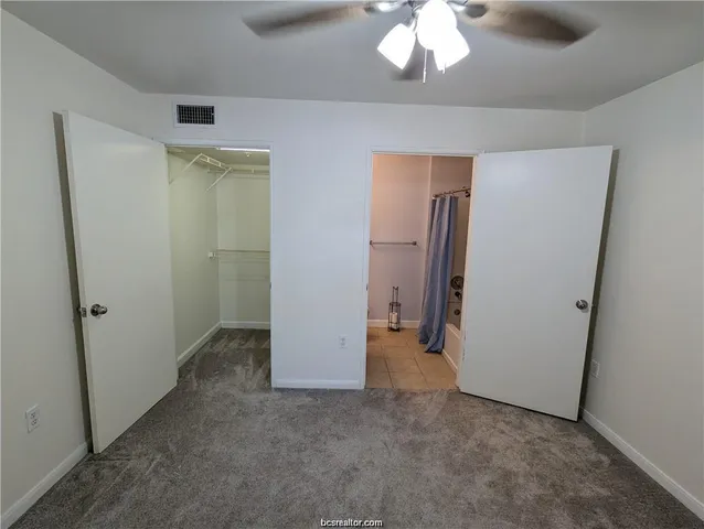 an empty room with a chandelier fan and closet