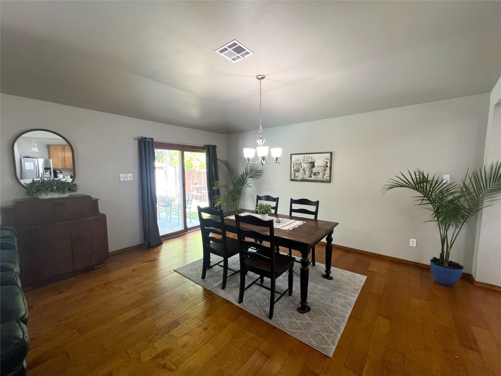404 Patton Cove Bastrop, TX 78602 - Photo 11 of 40 Dining room with wood finished floors, and an inviting chandelier