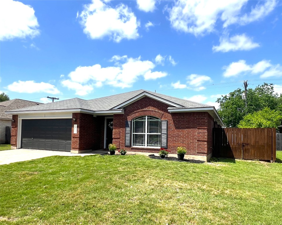 404 Patton Cove Bastrop, TX 78602 - Photo 2 of 40 Ranch-style home featuring a front lawn, driveway, fence, brick siding, and an attached garage
