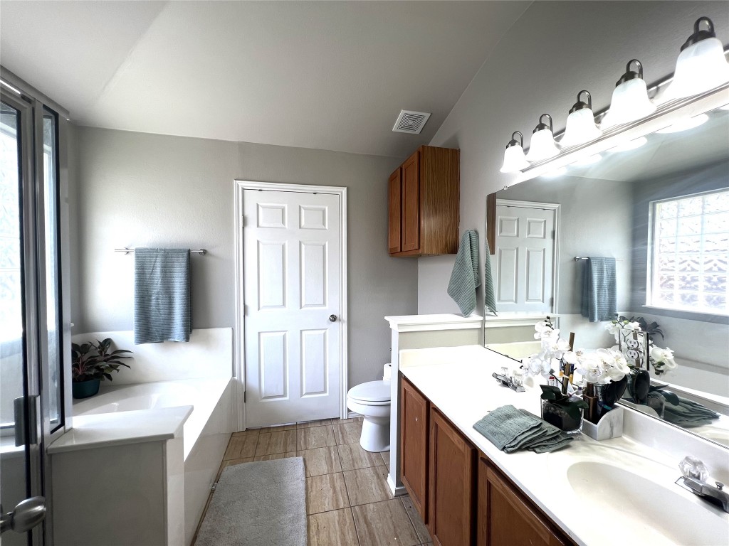404 Patton Cove Bastrop, TX 78602 - Photo 25 of 40 Bathroom with a garden tub, double sinks, and plenty of natural light