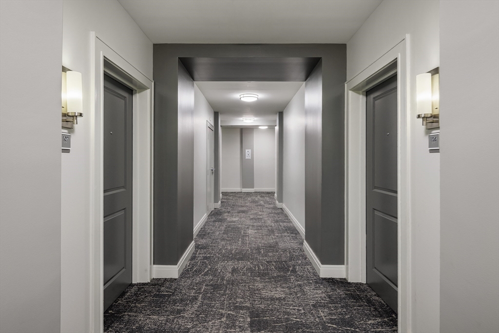 30 Mill Street, Unit 218 Arlington, MA 02476 - Photo 15 of 37 a view of a hallway with wooden floor and a bathroom