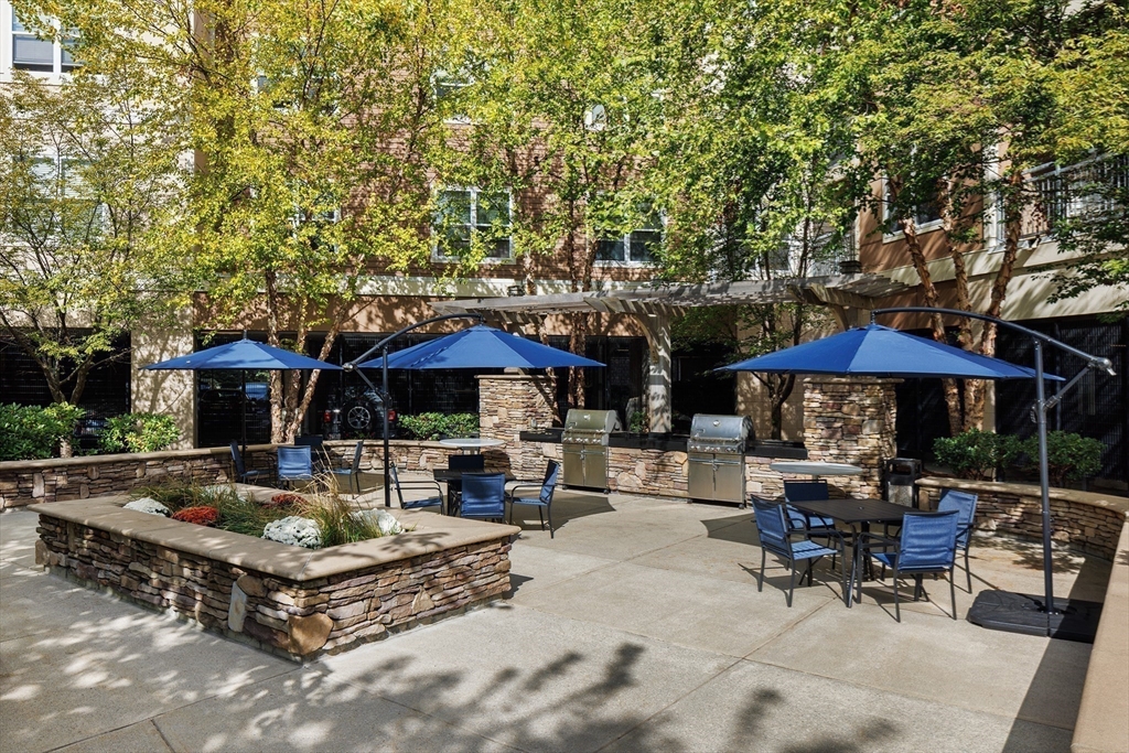 30 Mill Street, Unit 218 Arlington, MA 02476 - Photo 4 of 37 a backyard of a house with barbeque oven table and chairs