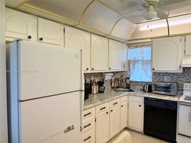a kitchen with granite countertop white refrigerator sink and cabinets
