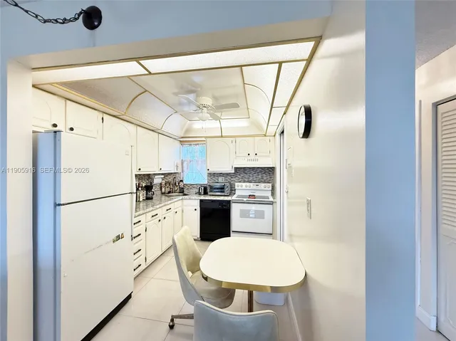 a kitchen with refrigerator a stove a sink and white cabinets with wooden floor